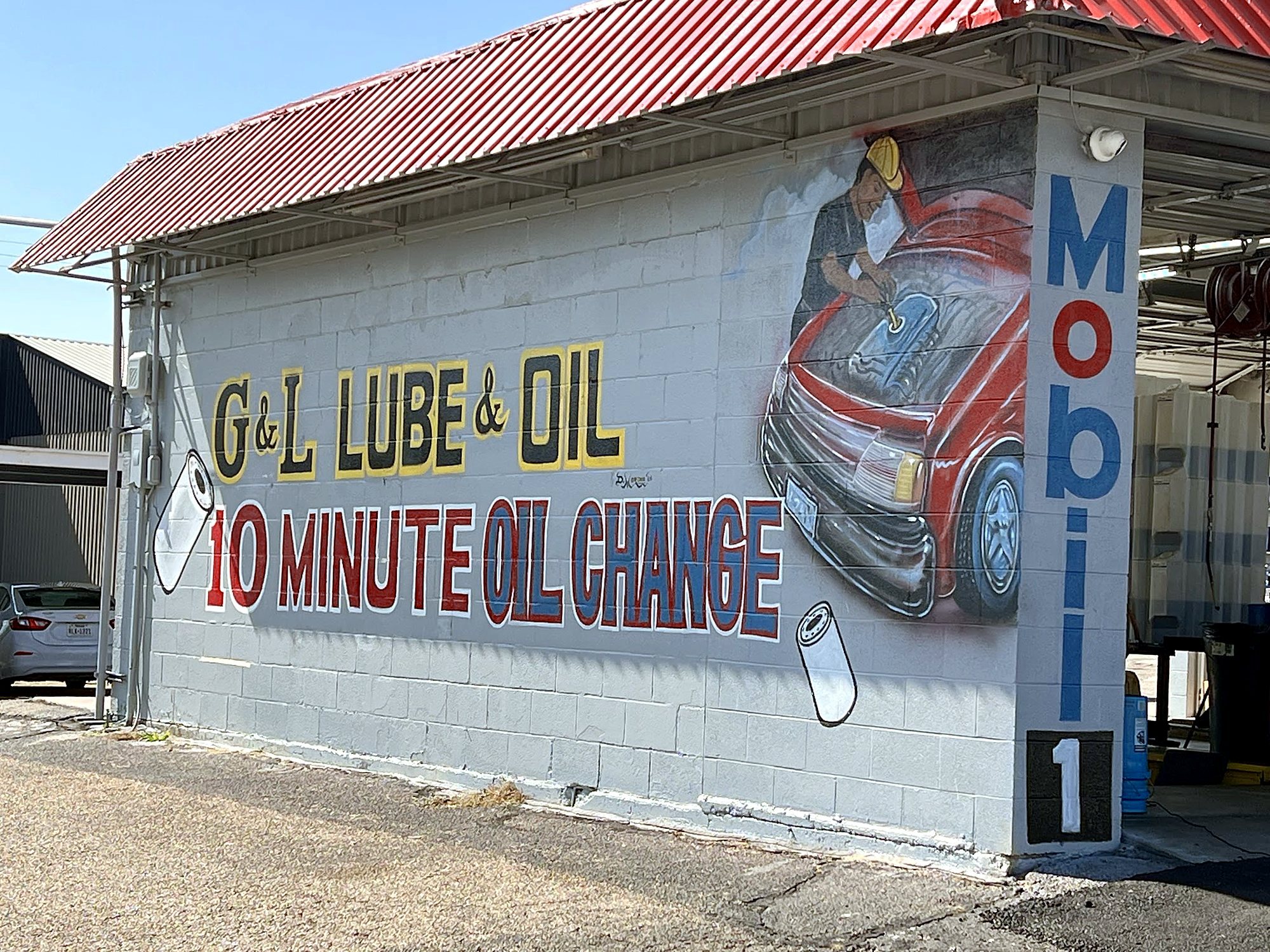 The side wall: G&L Lube & Oil, 10 Minute Oil Change, hand-painted in red, yellow and blue on gray block
