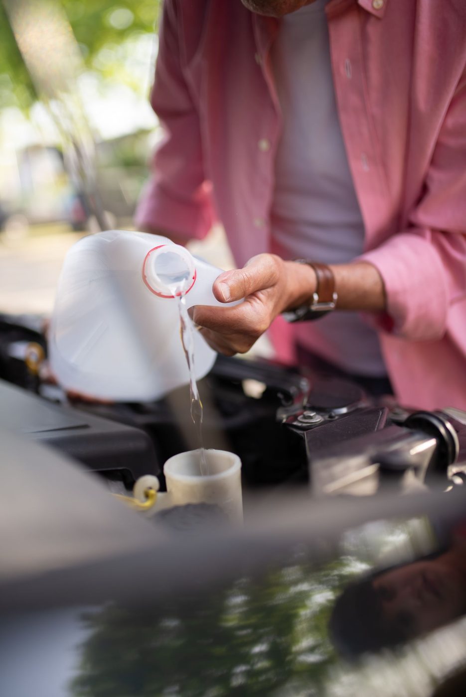 Fluid being poured into a reservoir under the hood