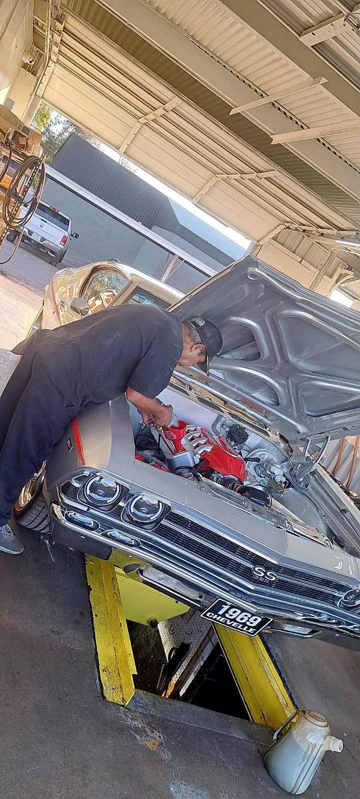 A tech working on a 1969 Chevelle over the pit
