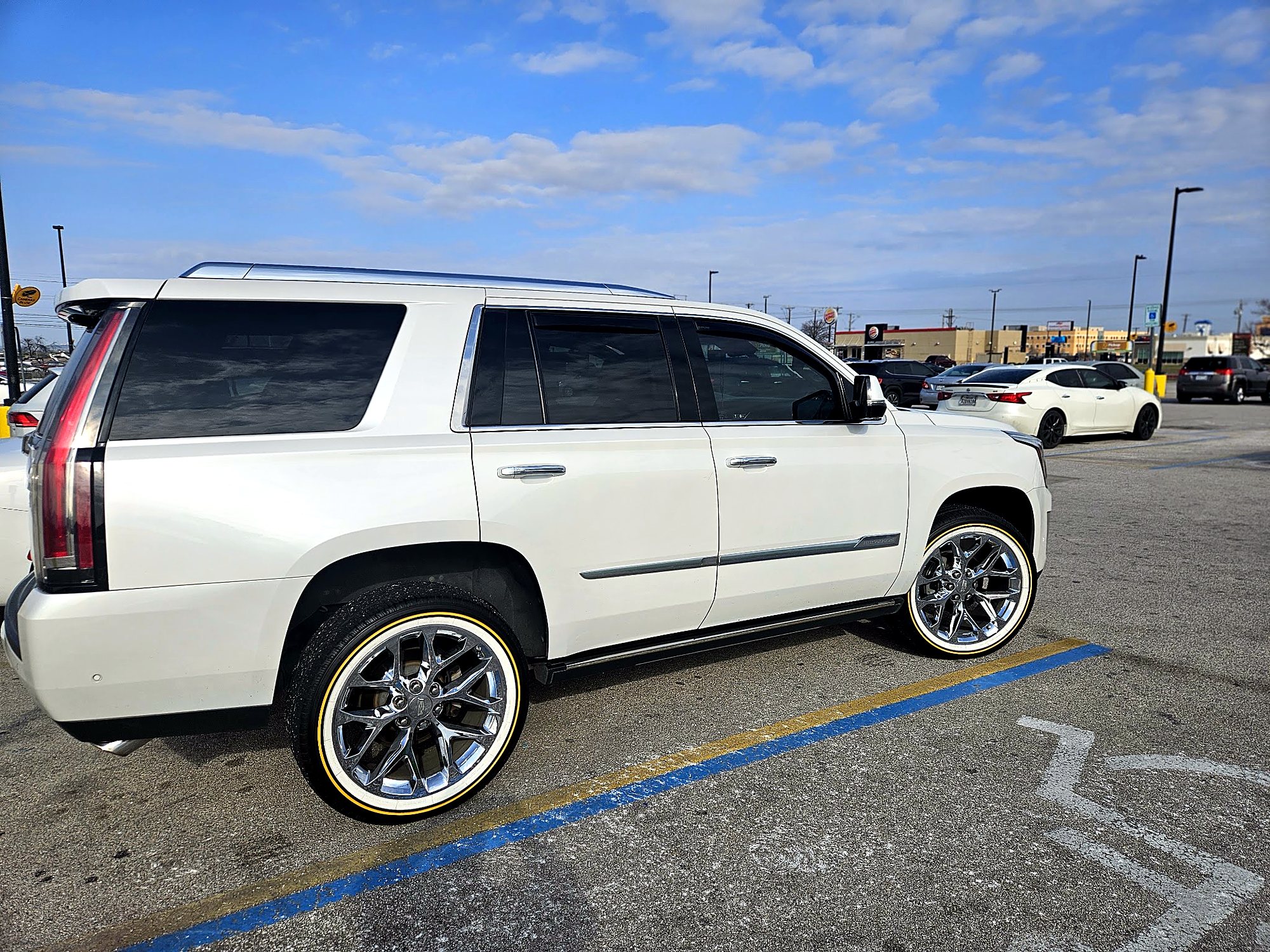 A white Cadillac Escalade on chrome wheels outside the shop